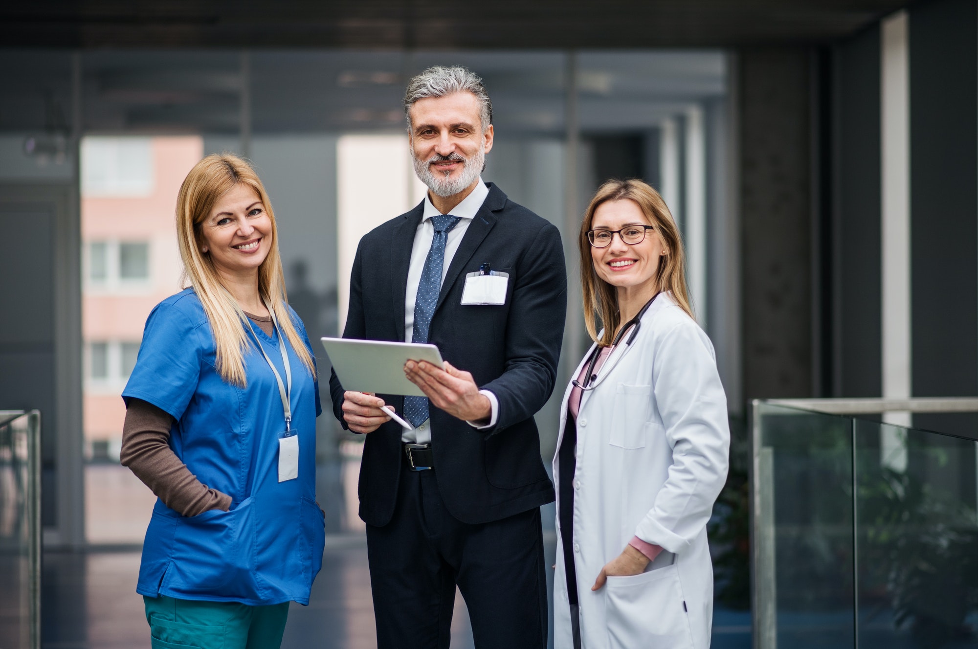 Doctors with pharmaceutical manager standing in corridor.